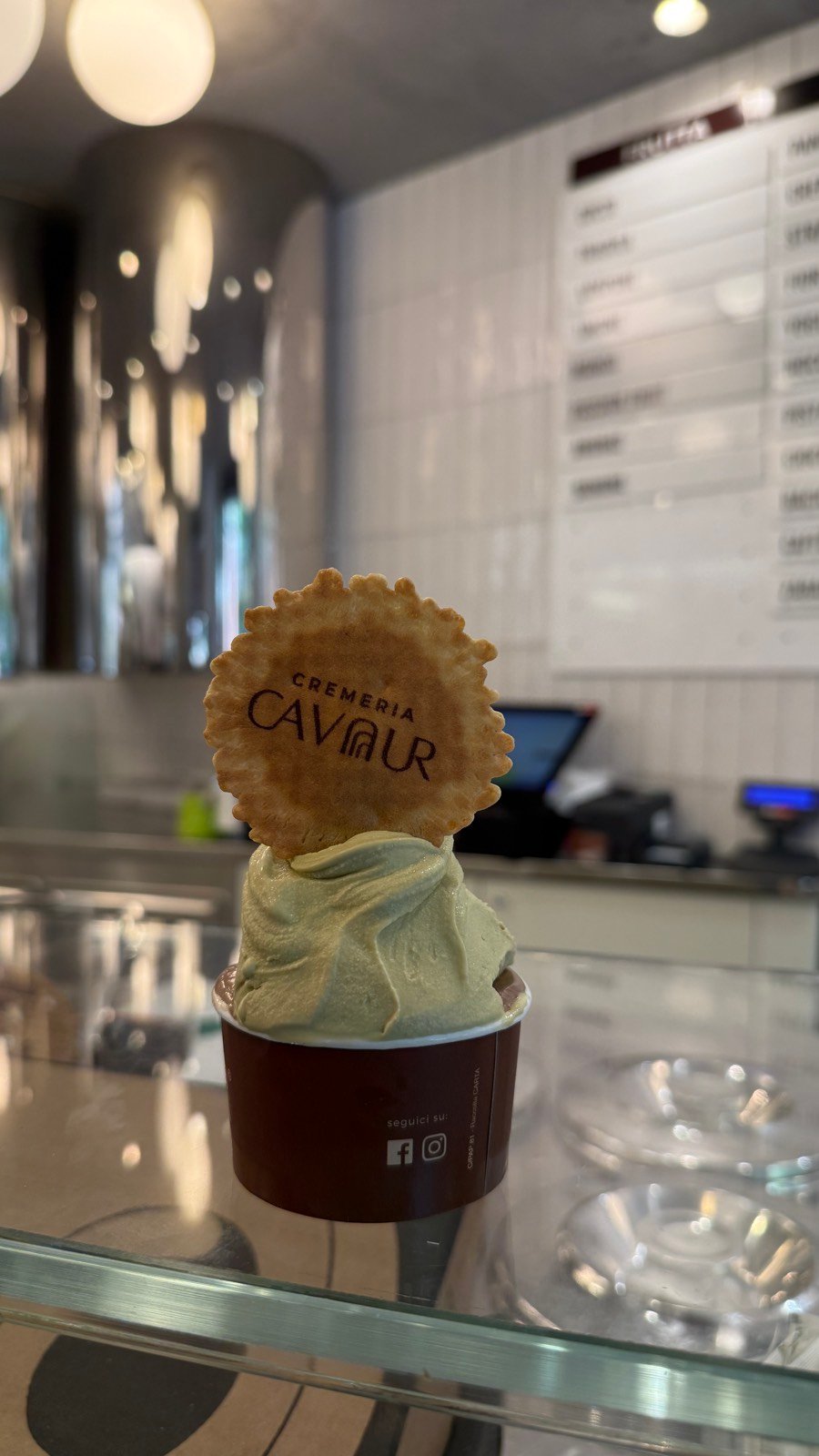 A cup of pistachio gelato with a wafer from Cremeria Cavour in Bologna