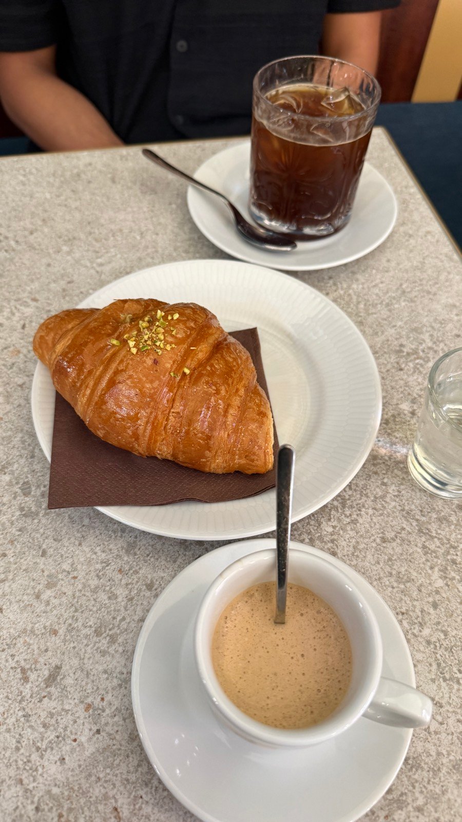 A pistachio croissant with an espresso and an iced americano at Denso coffee bar in Bologna