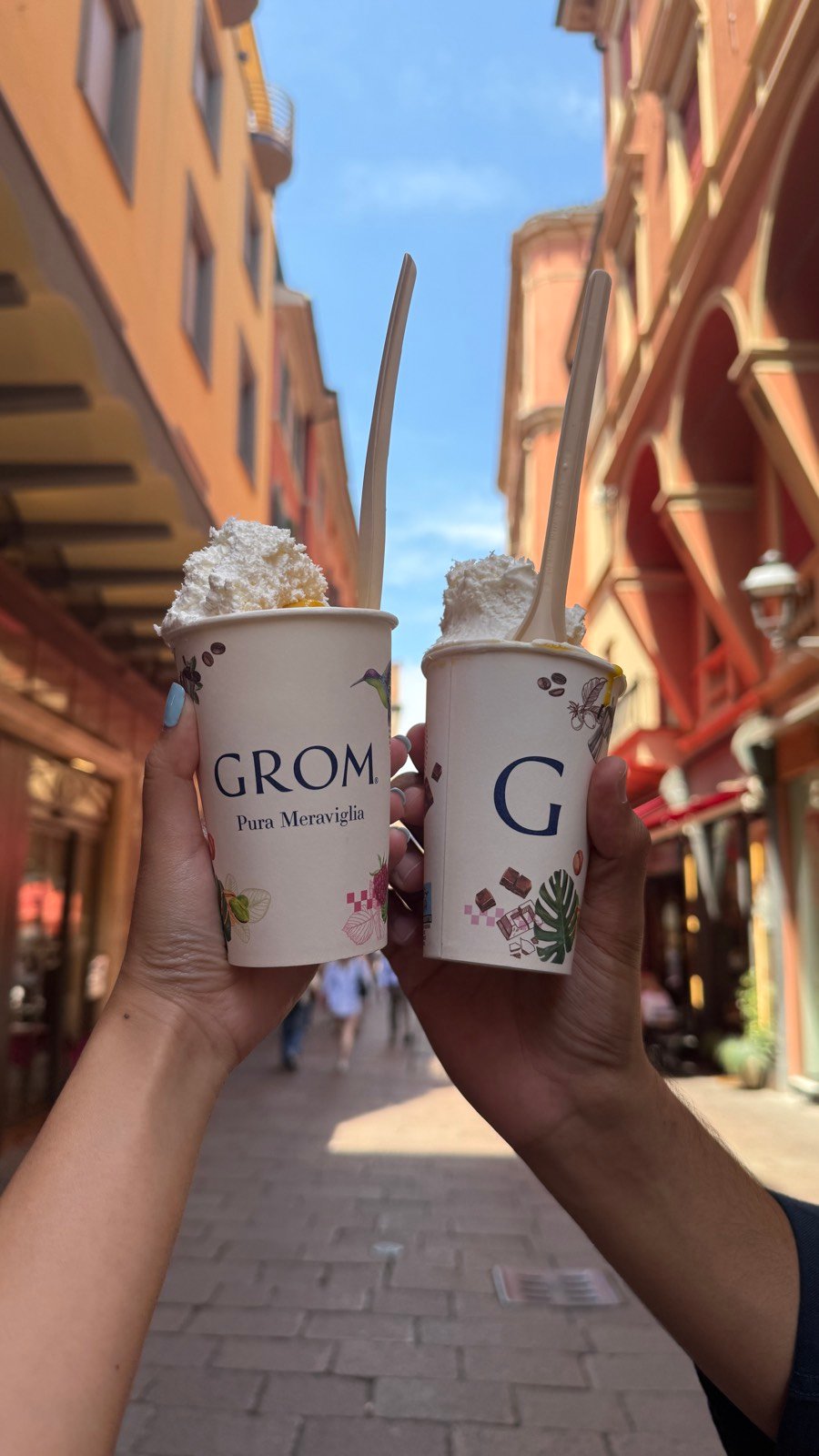 Two cups of granita from Grom held up in a narrow street in Bologna
