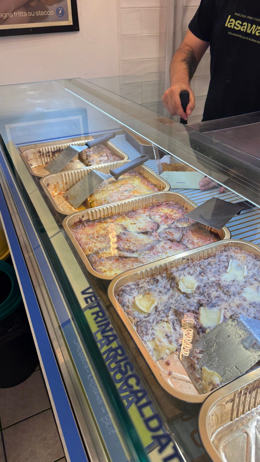 Trays of lasagna in a warming case at Lasaway takeaway in Bologna