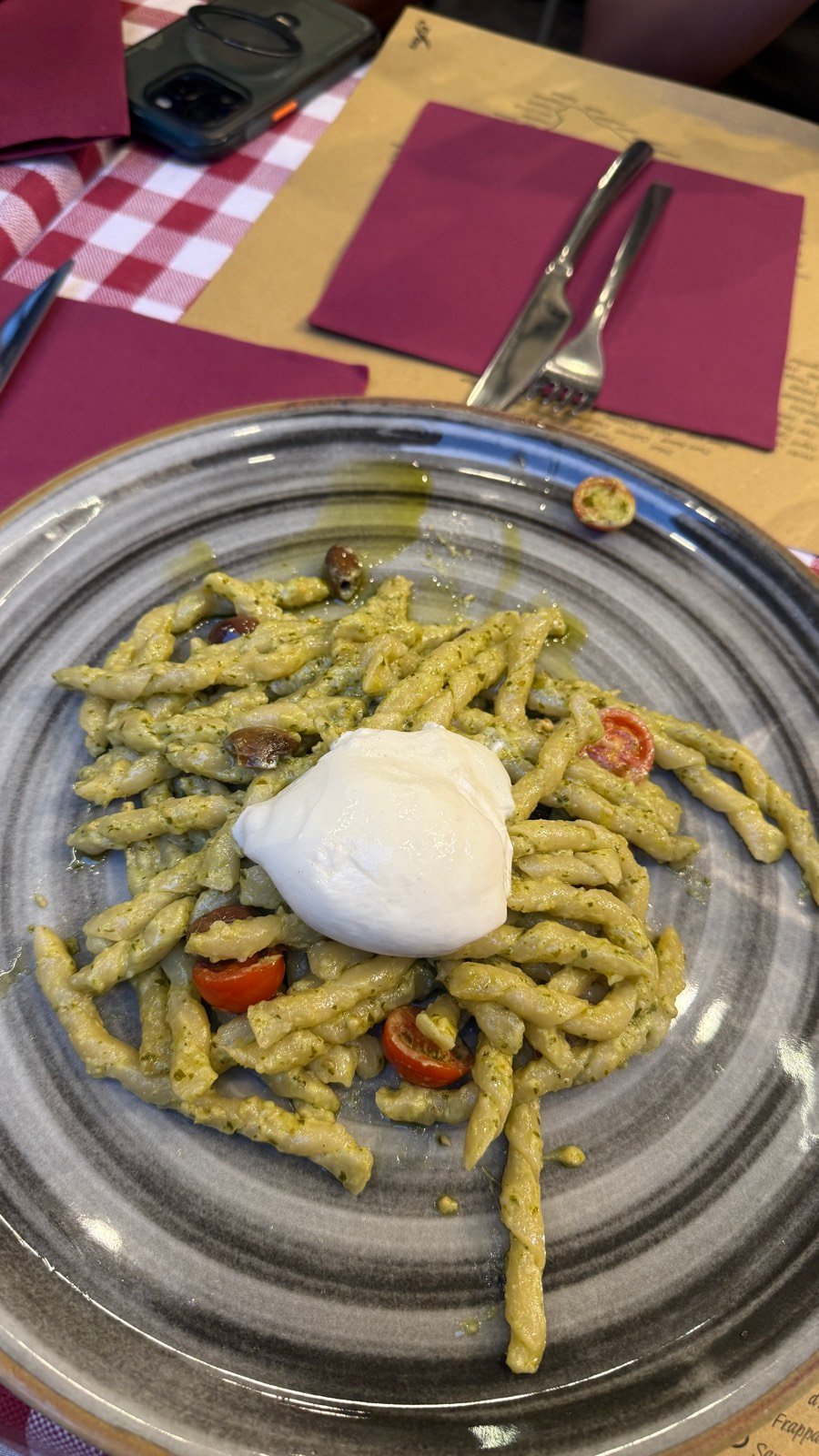 A plate of green pesto strozzapreti pasta topped with burrata at Mattarello in Bologna