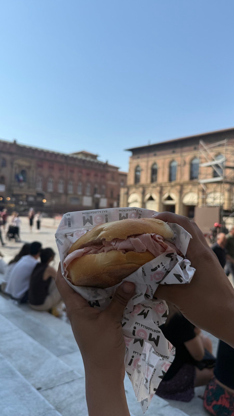 A mortadella sandwich held up in Piazza Maggiore in Bologna