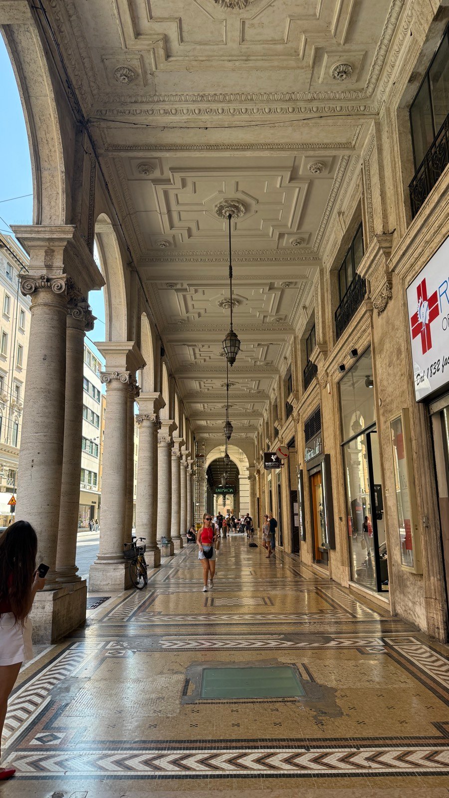 An elegant marble portico walkway along a shopping street in central Bologna