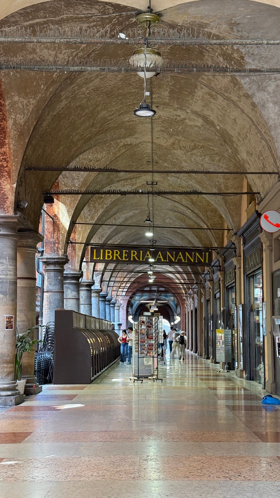 A vaulted portico walkway in Bologna running past the Libreria Nanni bookshop