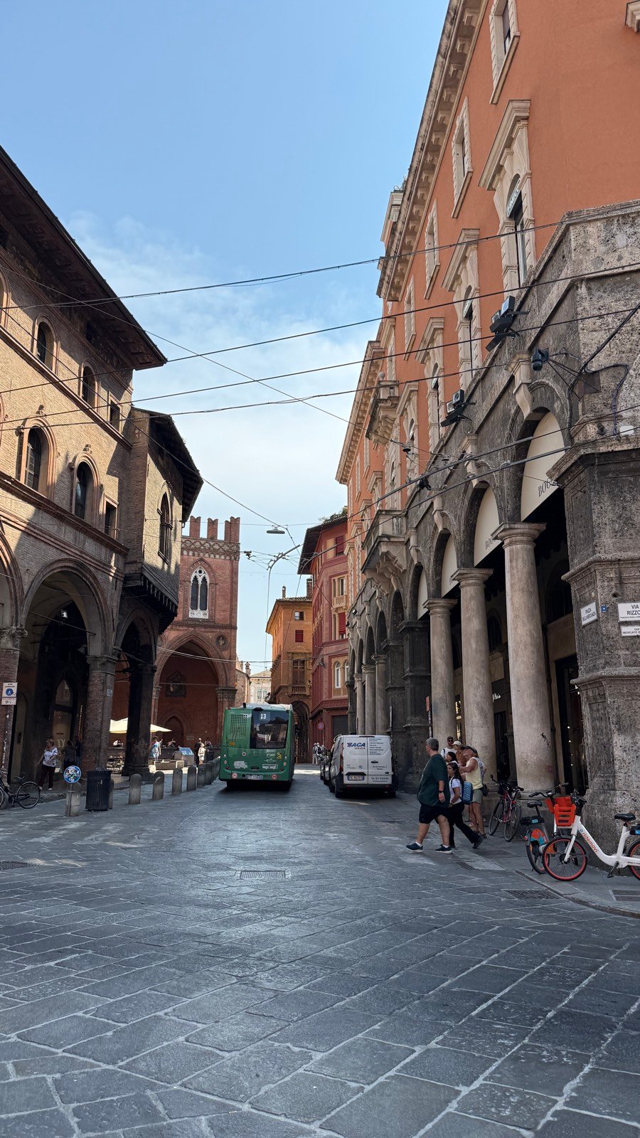 The two leaning medieval towers of Bologna, Asinelli and Garisenda, seen down a portico-lined street