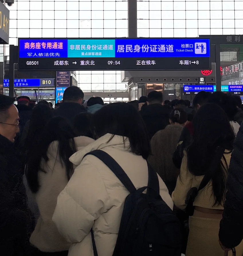Travellers queuing at a passport-scanning checkpoint inside a China train station