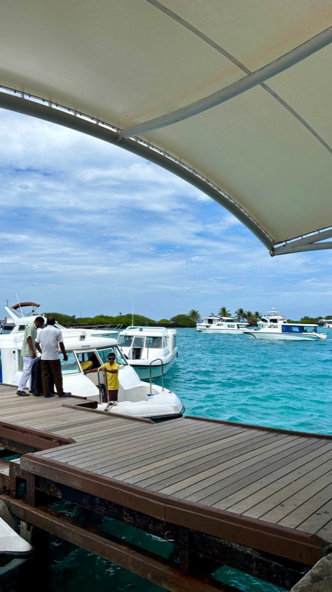Boats waiting at the airport jetty under a white canopy with turquoise water