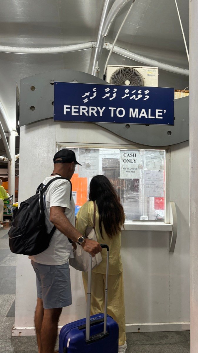 Travellers with luggage buying tickets at the Ferry to Male counter at Male airport