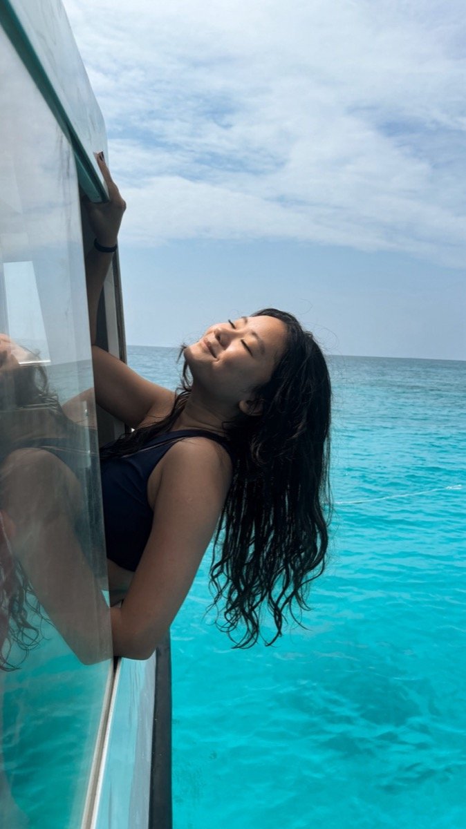 Alyssa leaning out of the tour boat window over bright turquoise water