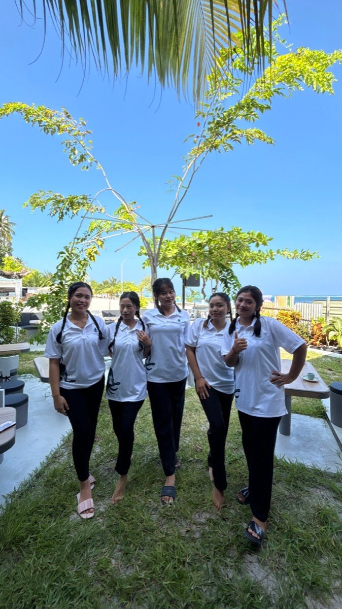 Five smiling staff members in matching uniforms in the garden at Island Catch on Maafushi