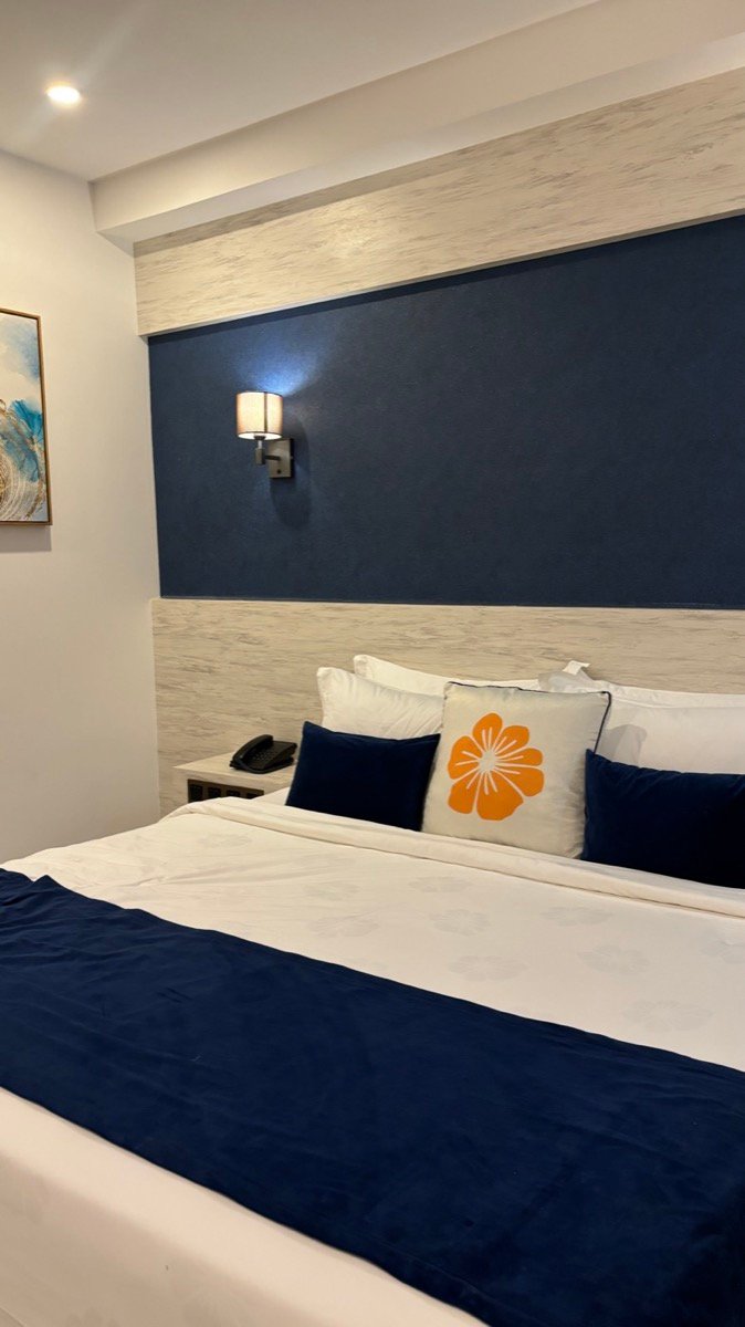 A double bed with navy and white linens in a room at Kaani Palm Beach on Maafushi