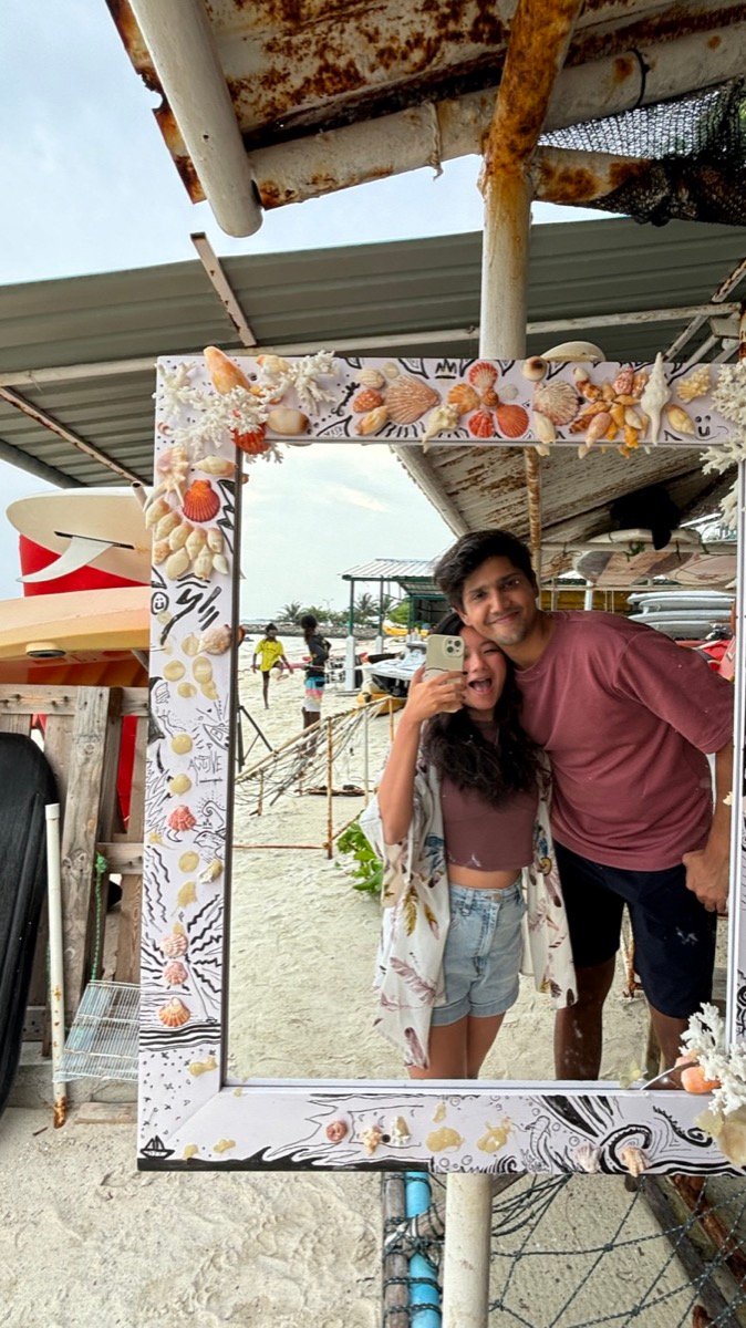 Alyssa and a friend taking a photo in a shell-framed mirror on the non-bikini beach on Maafushi