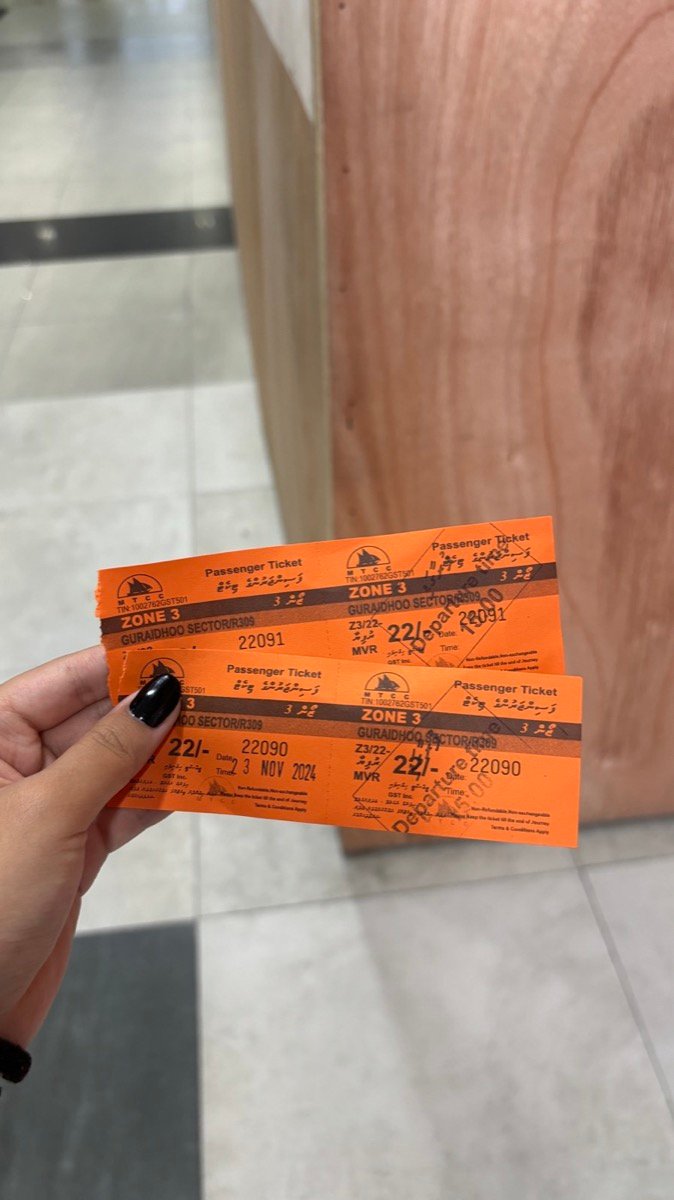 Two orange Male to Maafushi public ferry tickets held up in the terminal