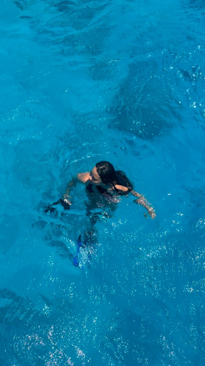 A snorkeler swimming in bright blue water seen from the boat