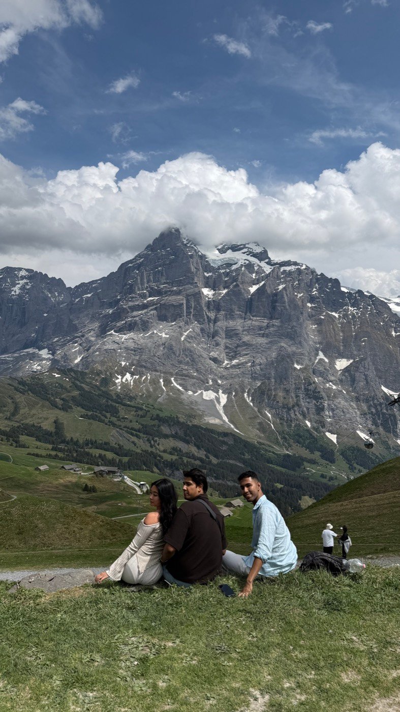 Sitting on the grass at Grindelwald First with the snow-streaked Wetterhorn massif and a gondola behind