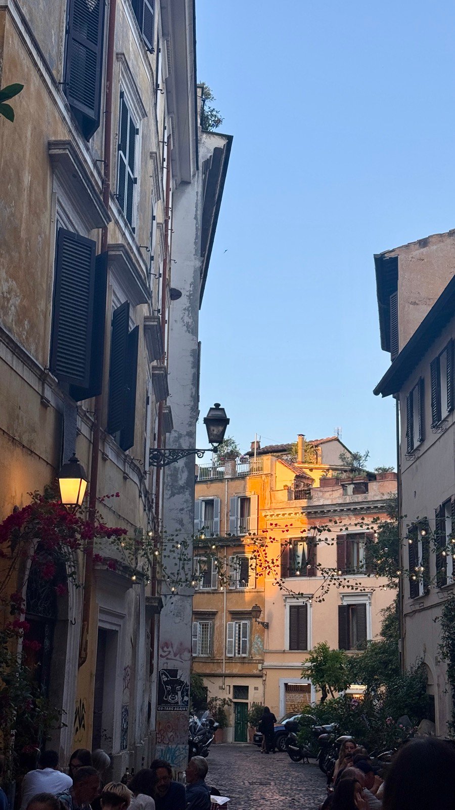 A Trastevere lane at dusk with string lights and diners in Rome